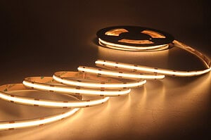 Warm white LED strip light unrolled, glowing brightly.