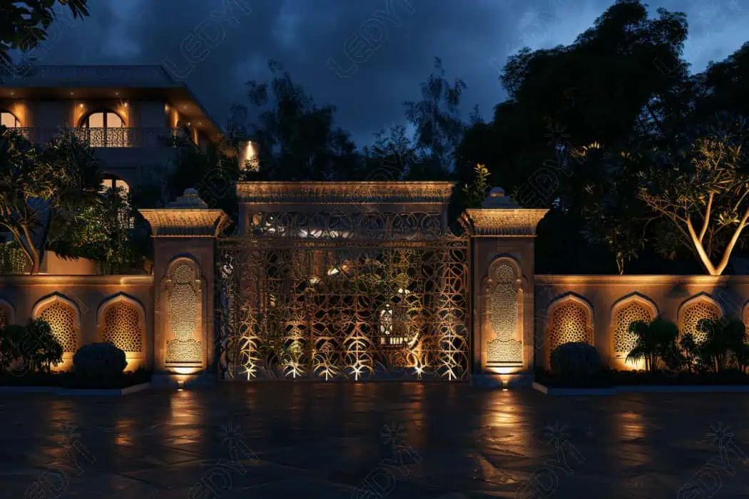 Portão ornamentado iluminado com design complexo à noite.