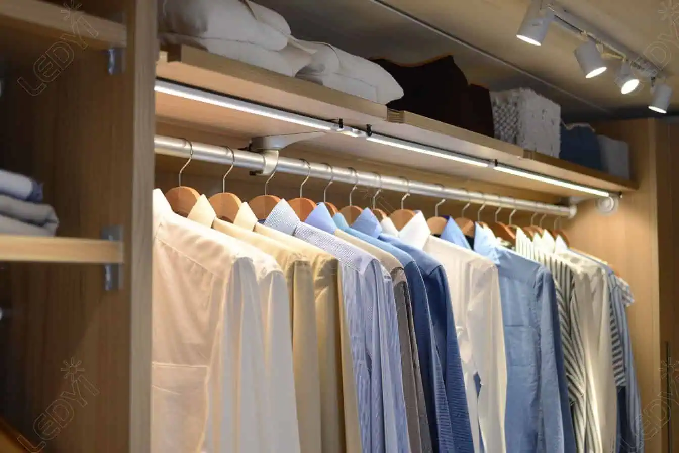 Neatly organized shirts hanging in a wooden closet.
